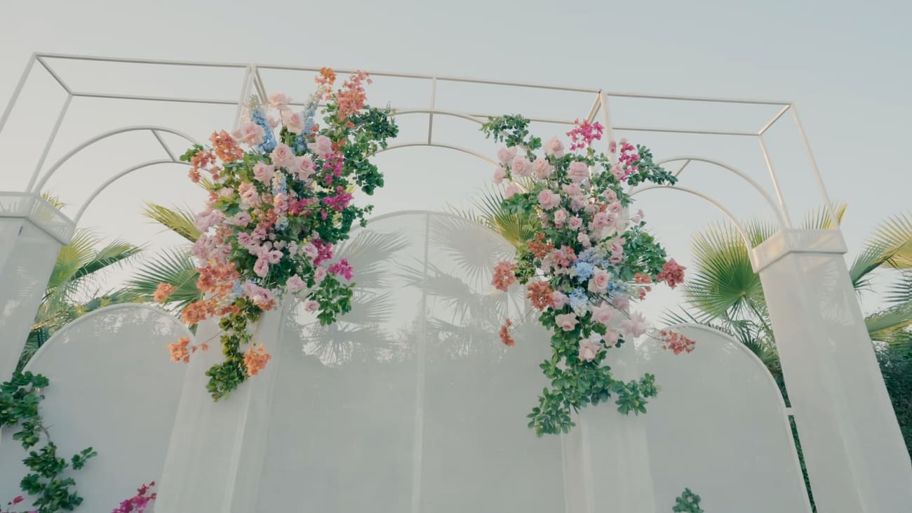 The ceremony arch dressed in roses, delphinium and bougainvillea