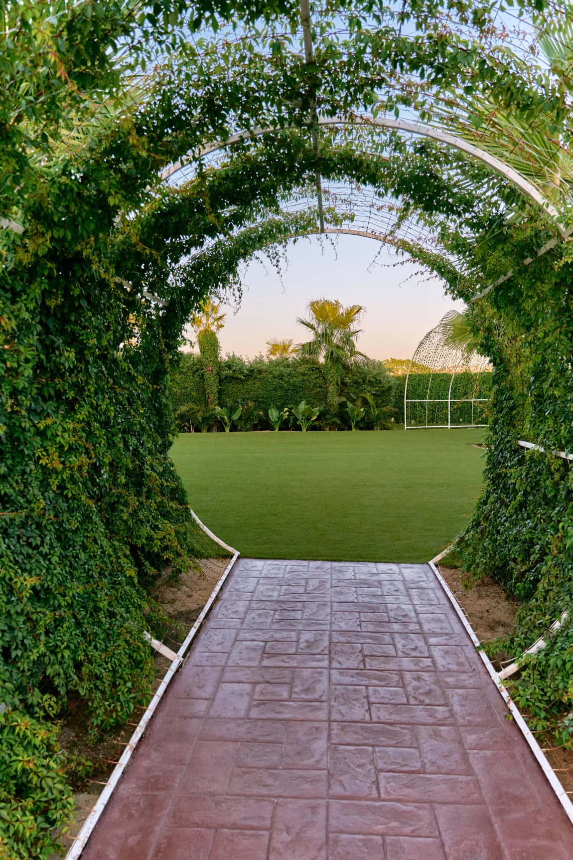 The planted arch opening onto the lawn, where the chuppah is set