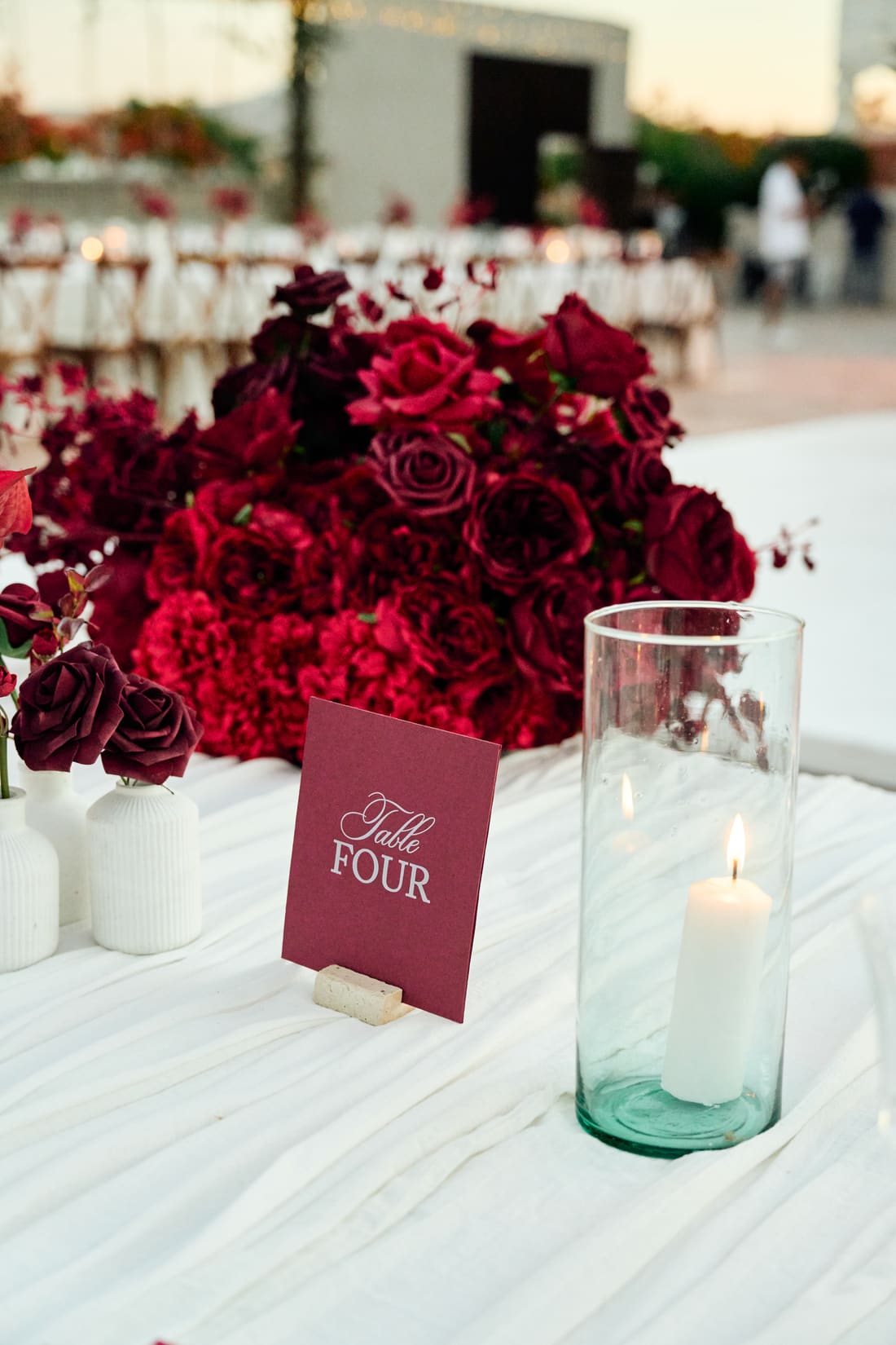 Crimson roses and candlelight on a long banquet table